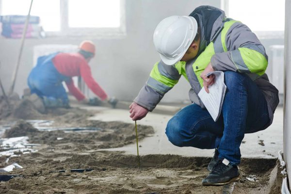 foreman builder engineer inspector measure floor covering at indoor construction site in new indoor flat apartment building